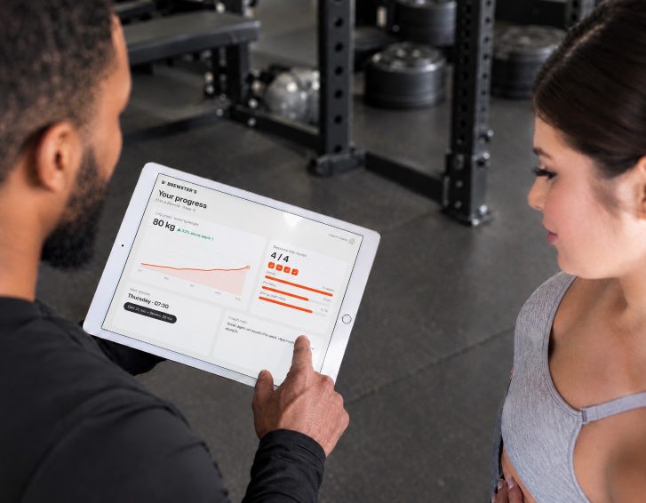Duane reviewing a client’s training progress on a tablet in the studio
