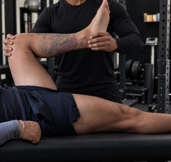 Duane stretching a client’s raised leg at Brewster’s studio